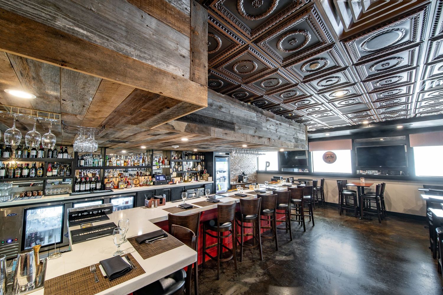 Industrial-style bar interior with exposed ceiling and long counter seating.