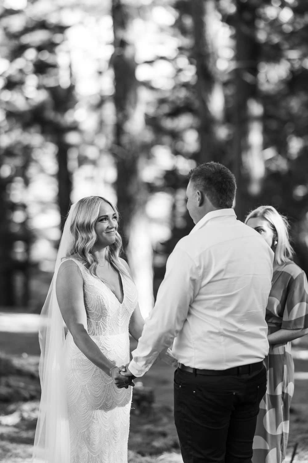 A series of black and white candid photos showing a couple in formal wedding attire embracing in an outdoor forest setting.