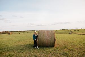 A sequence of seven countryside photos showing hay bales in green fields under cloudy skies at sunset.