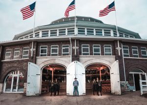 Historic brick building with three American flags flying on top and arched entrances.