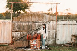 A rustic wooden fence with a tree branch stretches across a backyard setting at sunset.