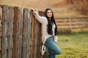 A horse and rider share a tender moment in a rustic barn setting during golden hour.