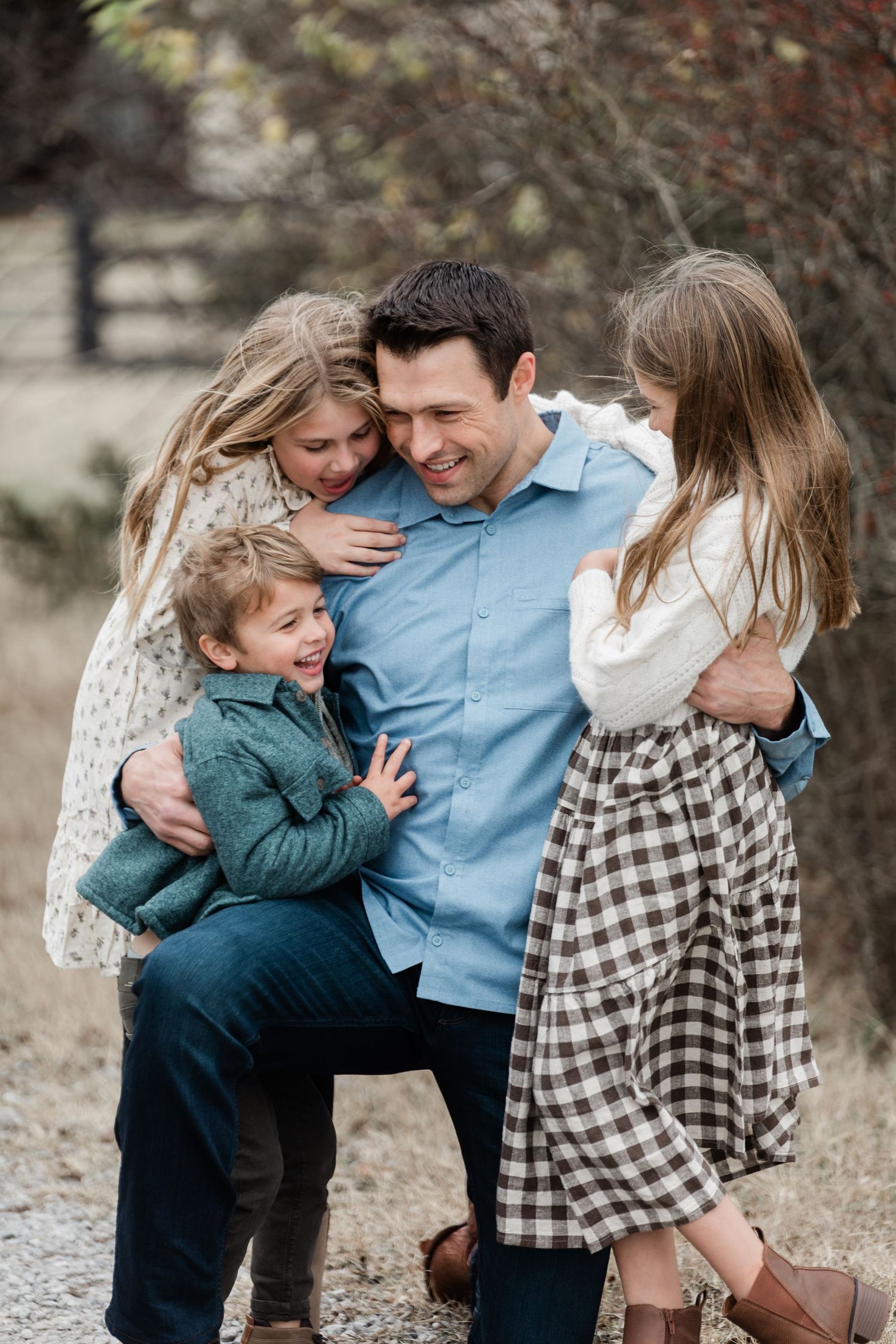 Family sharing joyful candid moments together during outdoor photo session against natural background.