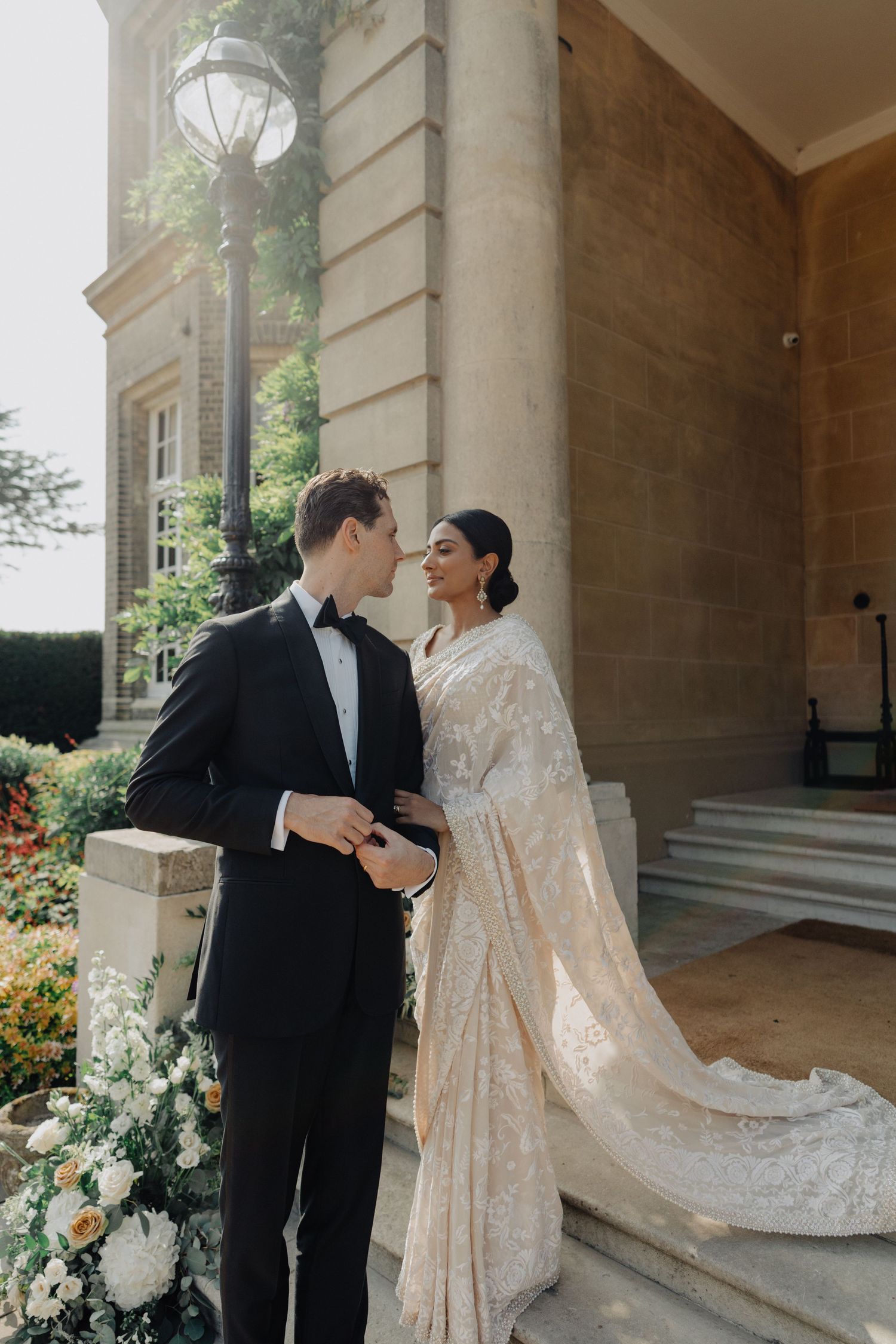Newlyweds share an intimate moment in a gazebo with brick details and greenery.
