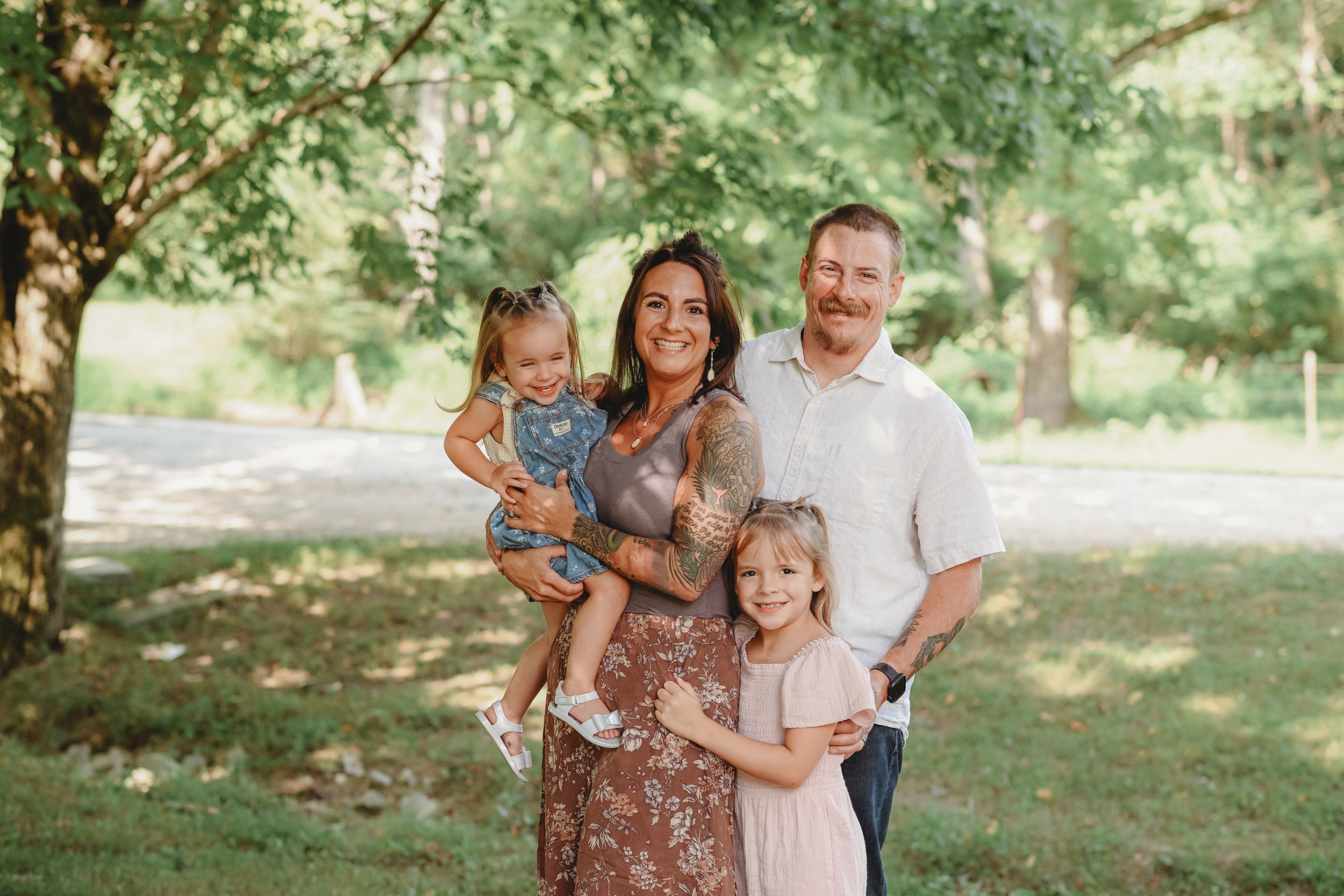 Family group photo taken under lush green trees in natural lighting.