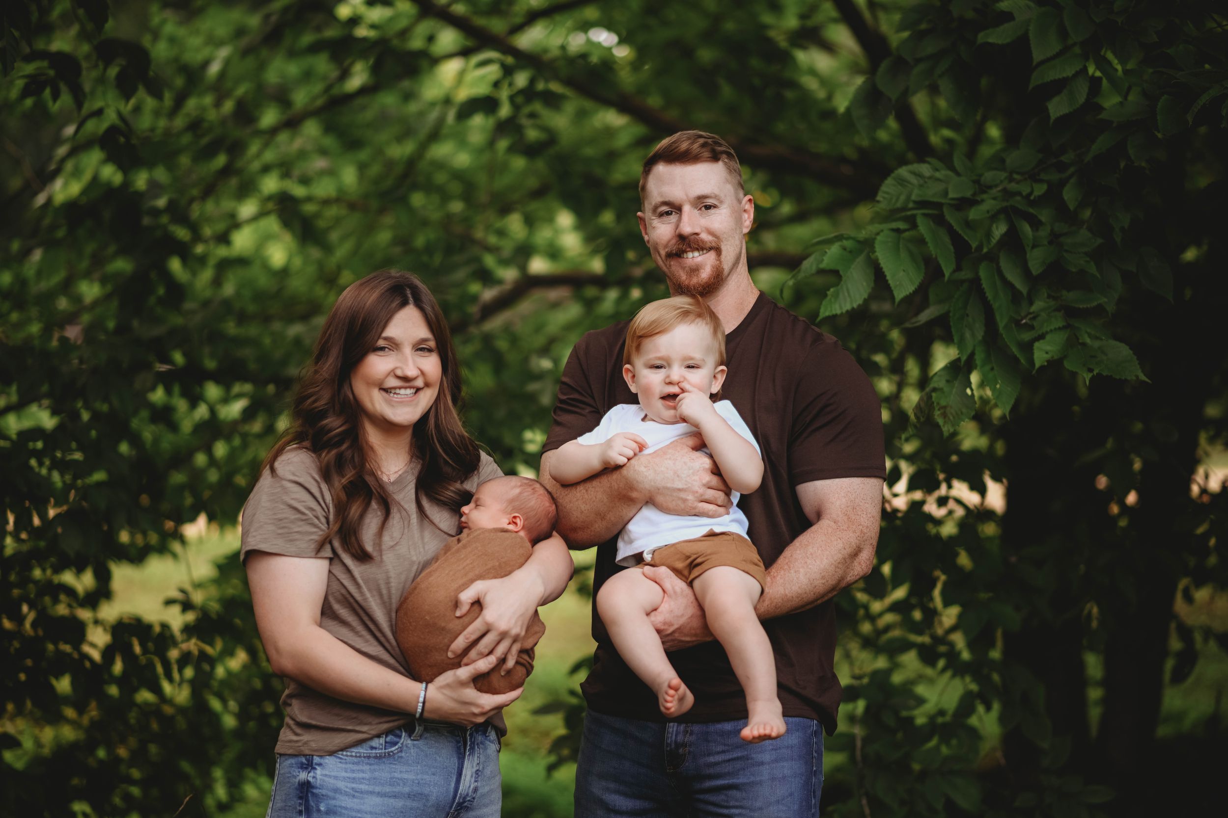 Intimate family portrait session in a wooded setting with natural greenery.