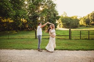 Romantic maternity photography session on path through scenic countryside at golden hour.