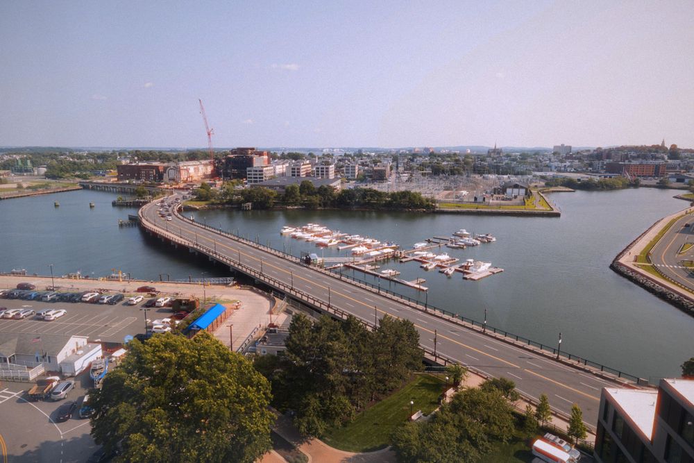 Aerial view of a coastal town with boats docked in a curved harbor marina.