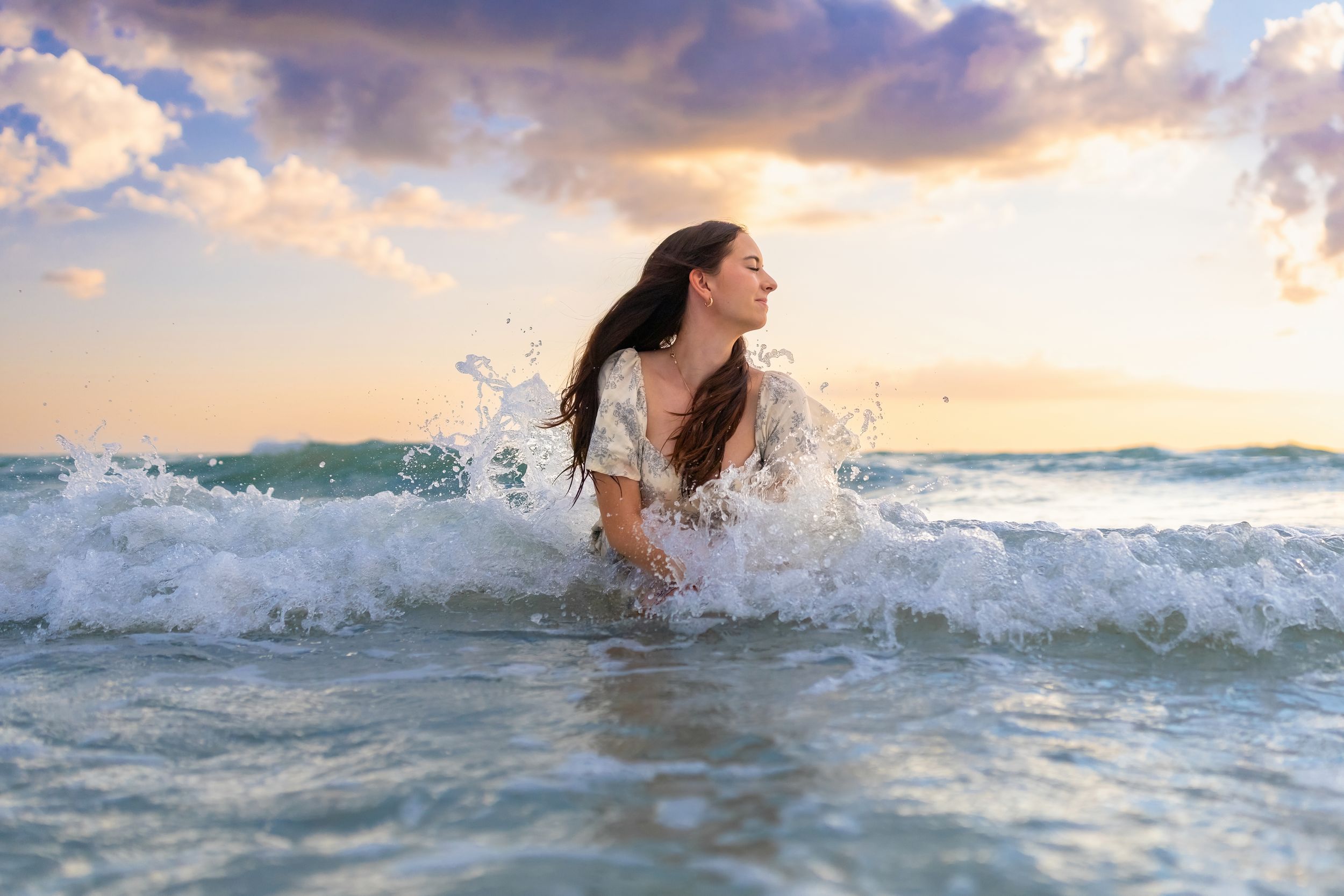 Person swimming in ocean waves at sunset with splashing water creating dynamic motion effect.