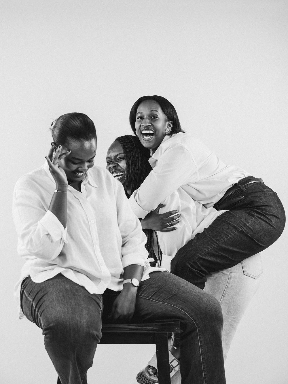 A playful sequence of black and white studio photos showing two people in white shirts and dark pants laughing together.