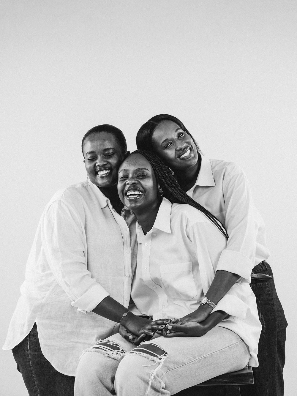 A joyful family portrait sequence in black and white showing playful poses and loving interactions against a white backdrop.