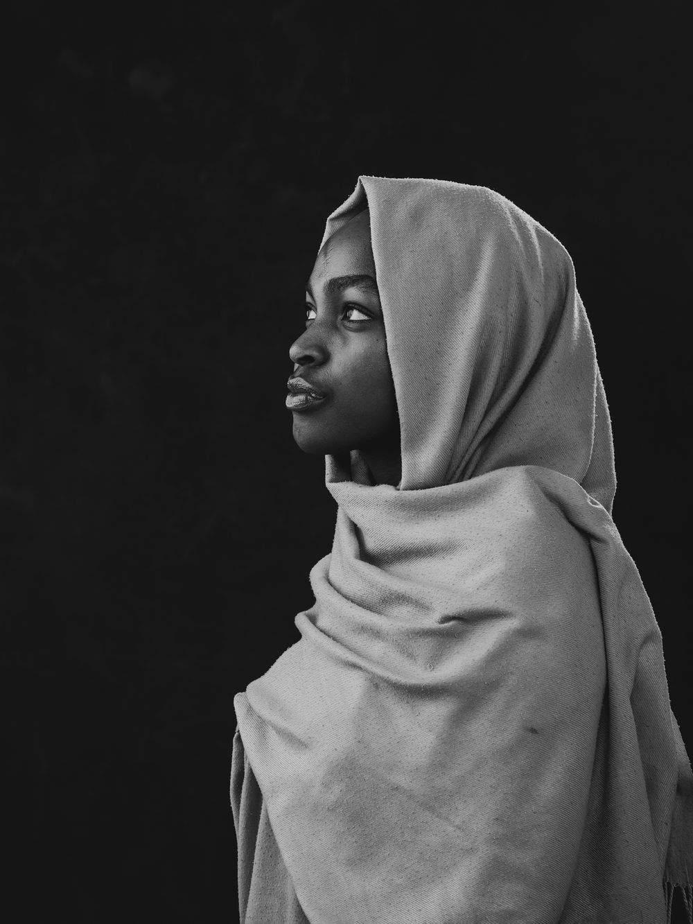 Sequential black and white profile portraits show a person in a light colored hijab against a dark background.