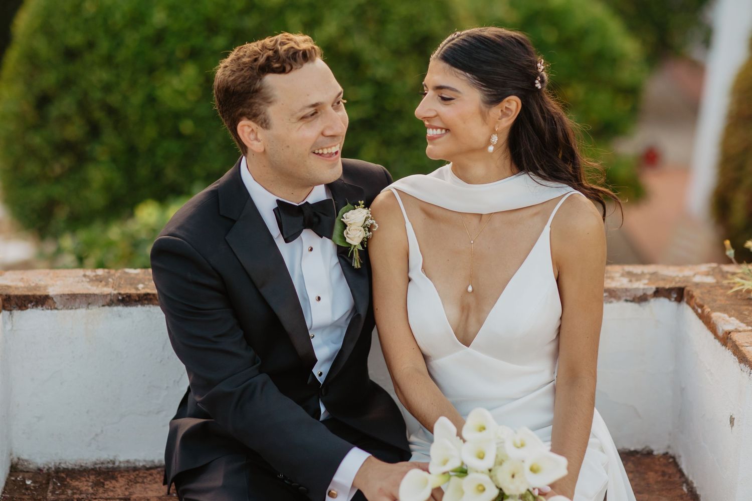 Romantic couple embraces in a scenic vineyard at sunset with warm golden light filtering through the grapevines.