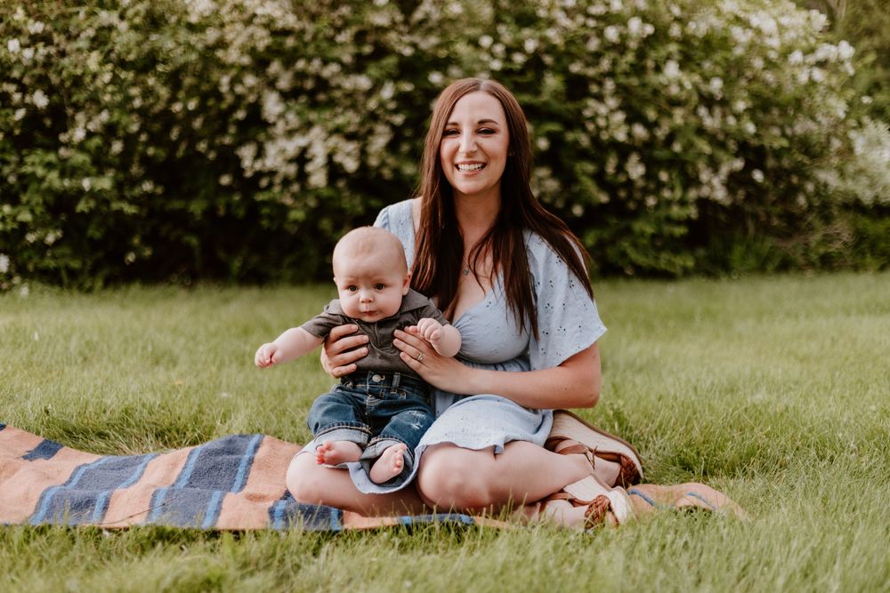Family enjoying a relaxing picnic together on a blanket in a sunny green grass field.