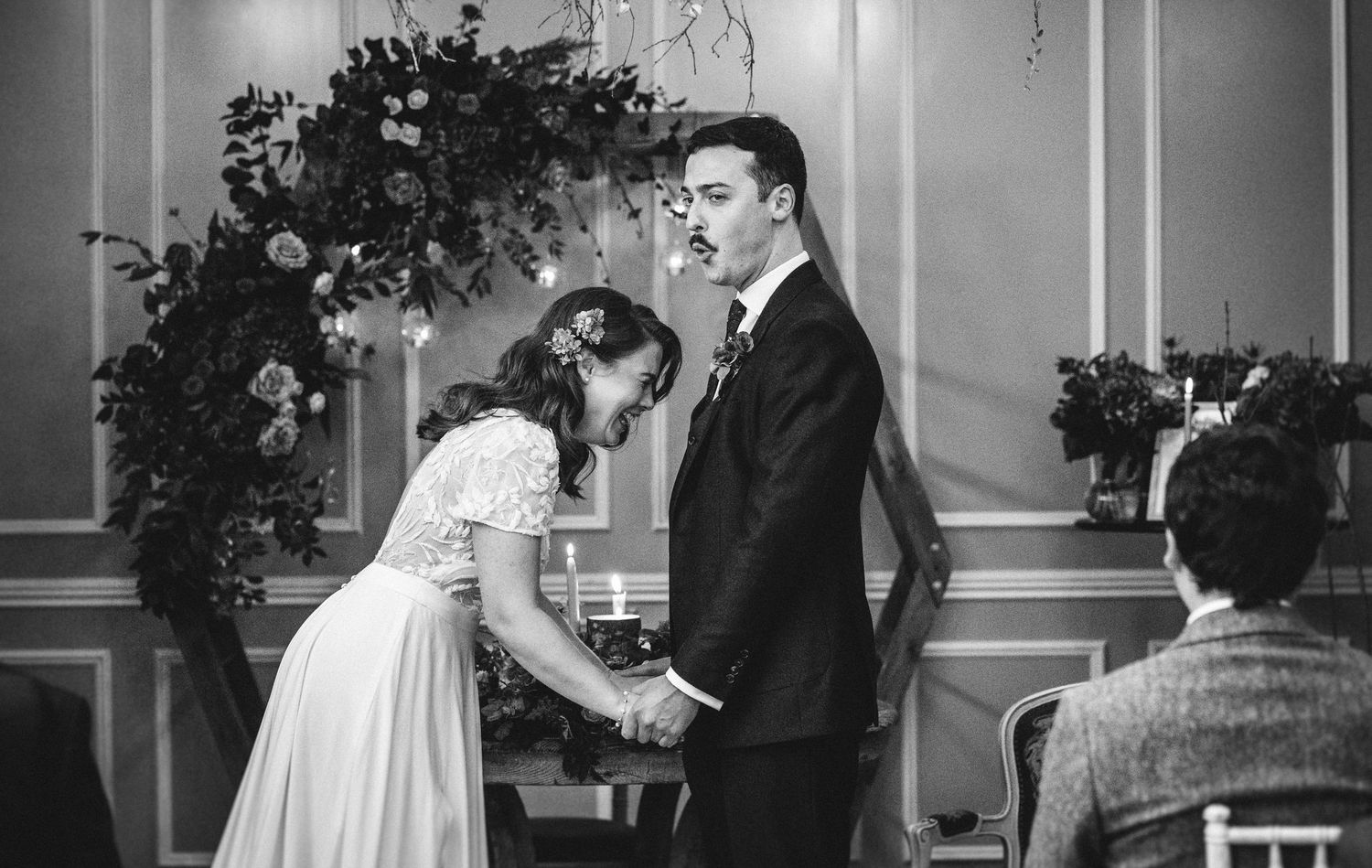 Black and white photo of newlyweds walking through crowd of celebrating wedding guests.