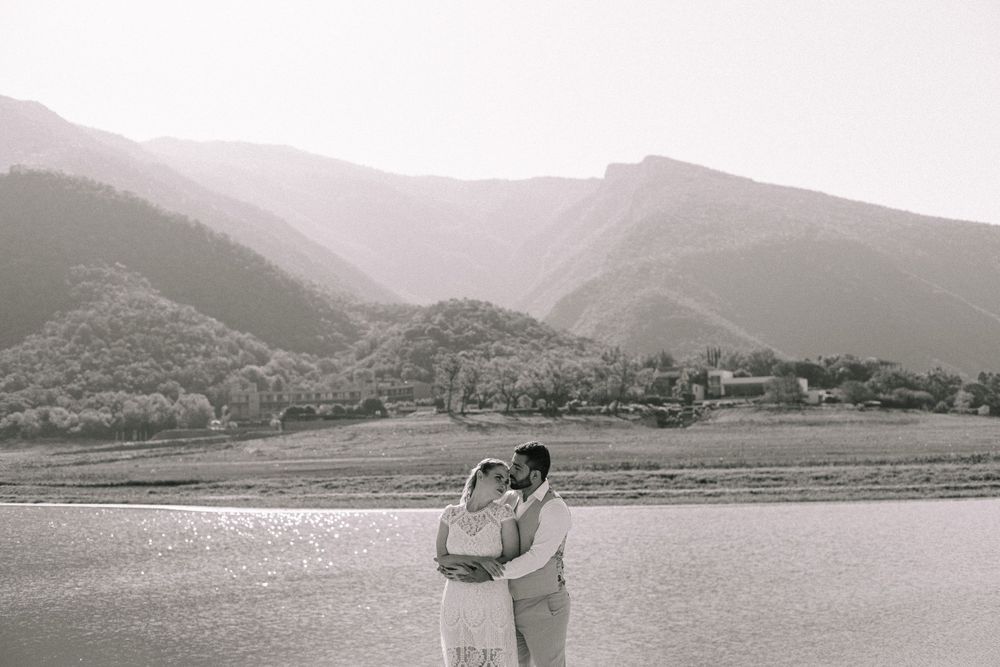 Wedding couple poses against a scenic mountain lake landscape.