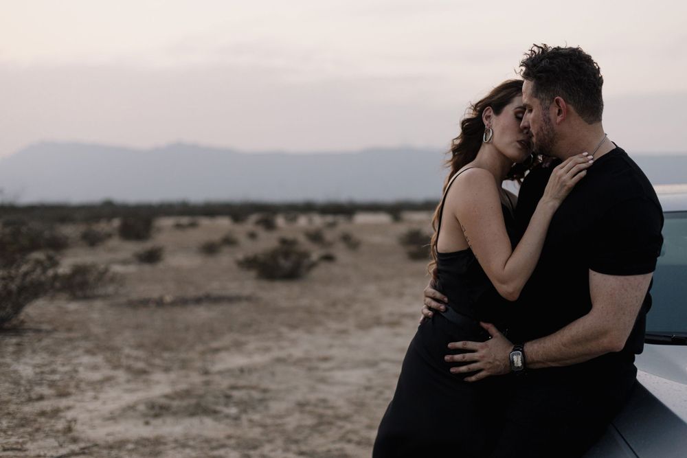 Intimate desert photoshoot with soft natural lighting and mountain backdrop.