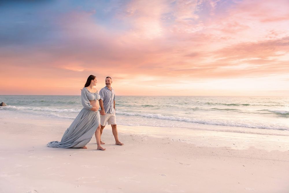 A romantic beach photoshoot at sunset with gentle waves rolling onto shore.