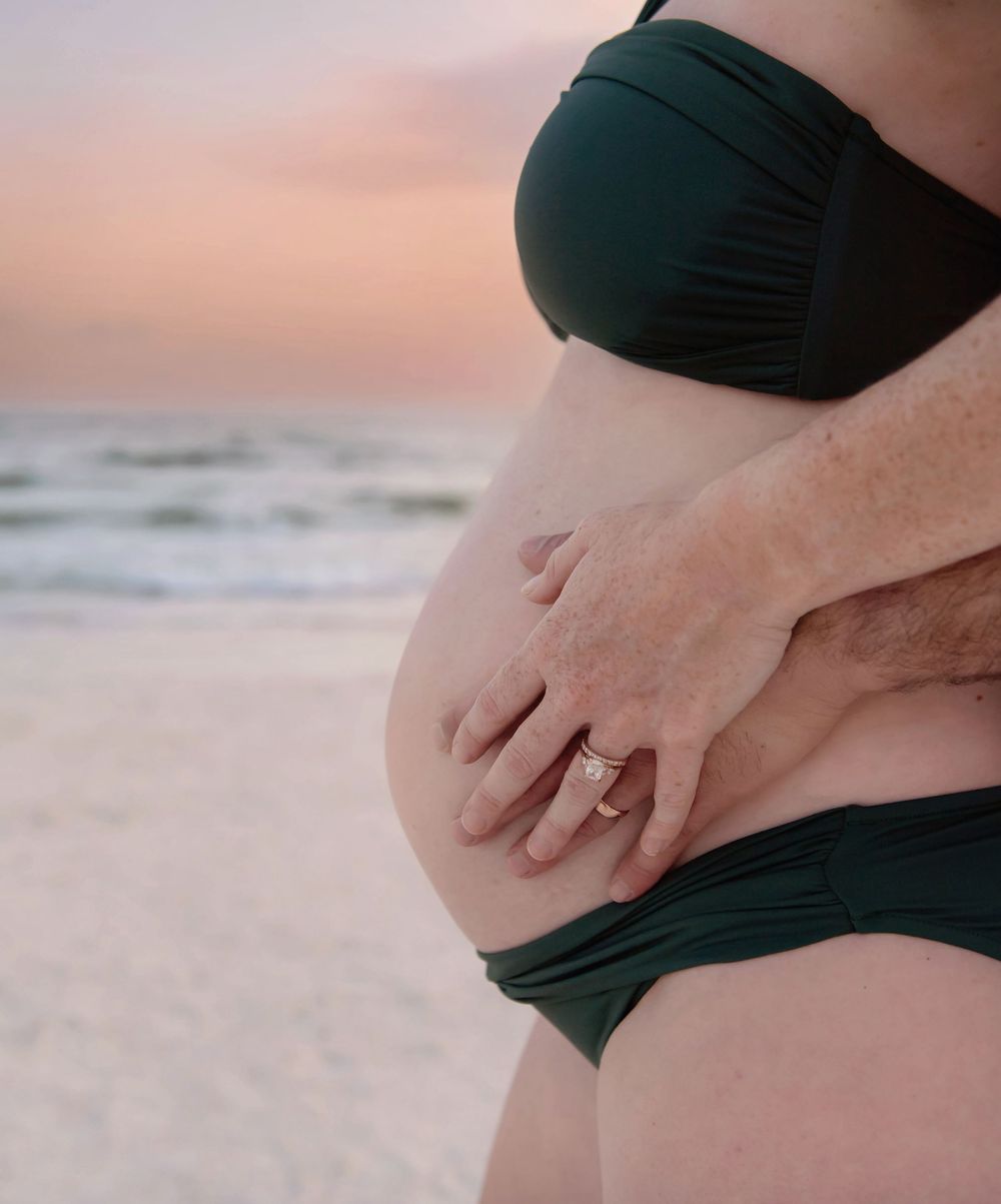 Close-up maternity photos showing pregnant belly on beach at sunset.