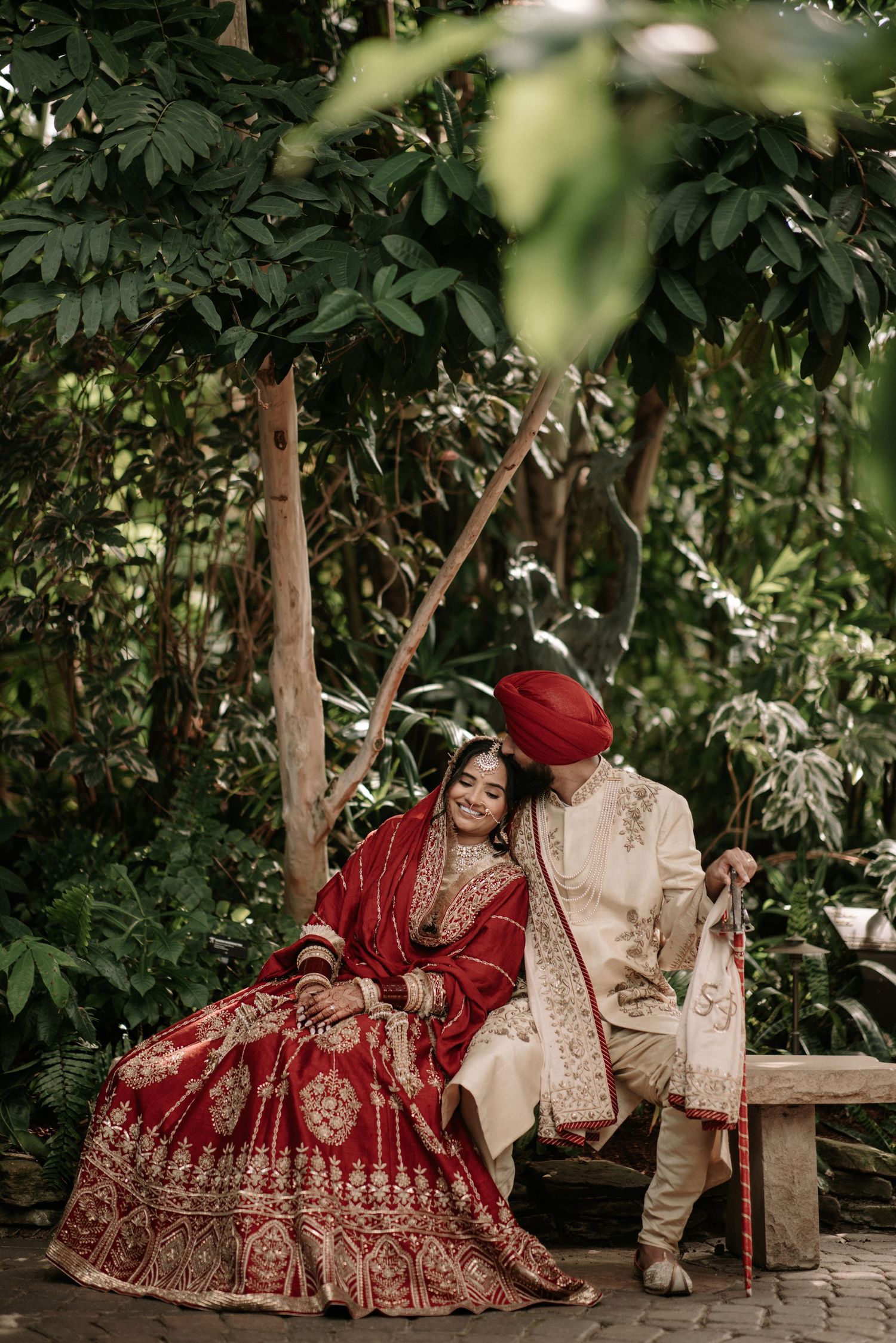 Bride in sparkly pink lehenga twirls as groom watches in traditional white attire.
