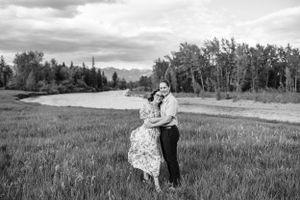 A black and white photo of a couple embracing in a mountain meadow.