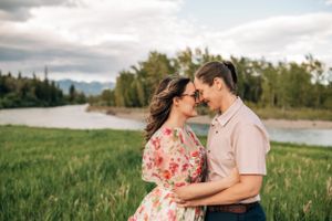 A romantic portrait of a couple in an intimate embrace against a scenic mountain landscape.