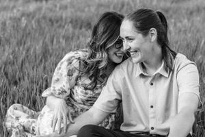 A black and white portrait captures a couple sharing laughter in a natural outdoor setting.
