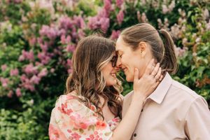 A tender moment shared between two people against a backdrop of blooming pink flowers.