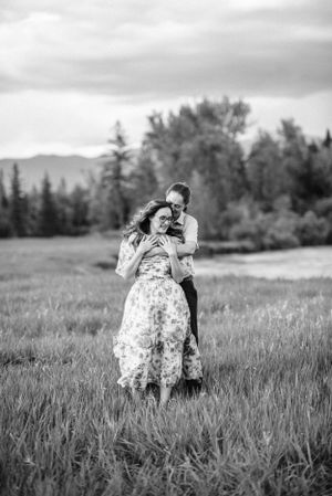 A black and white portrait of two people embracing in a mountain meadow.