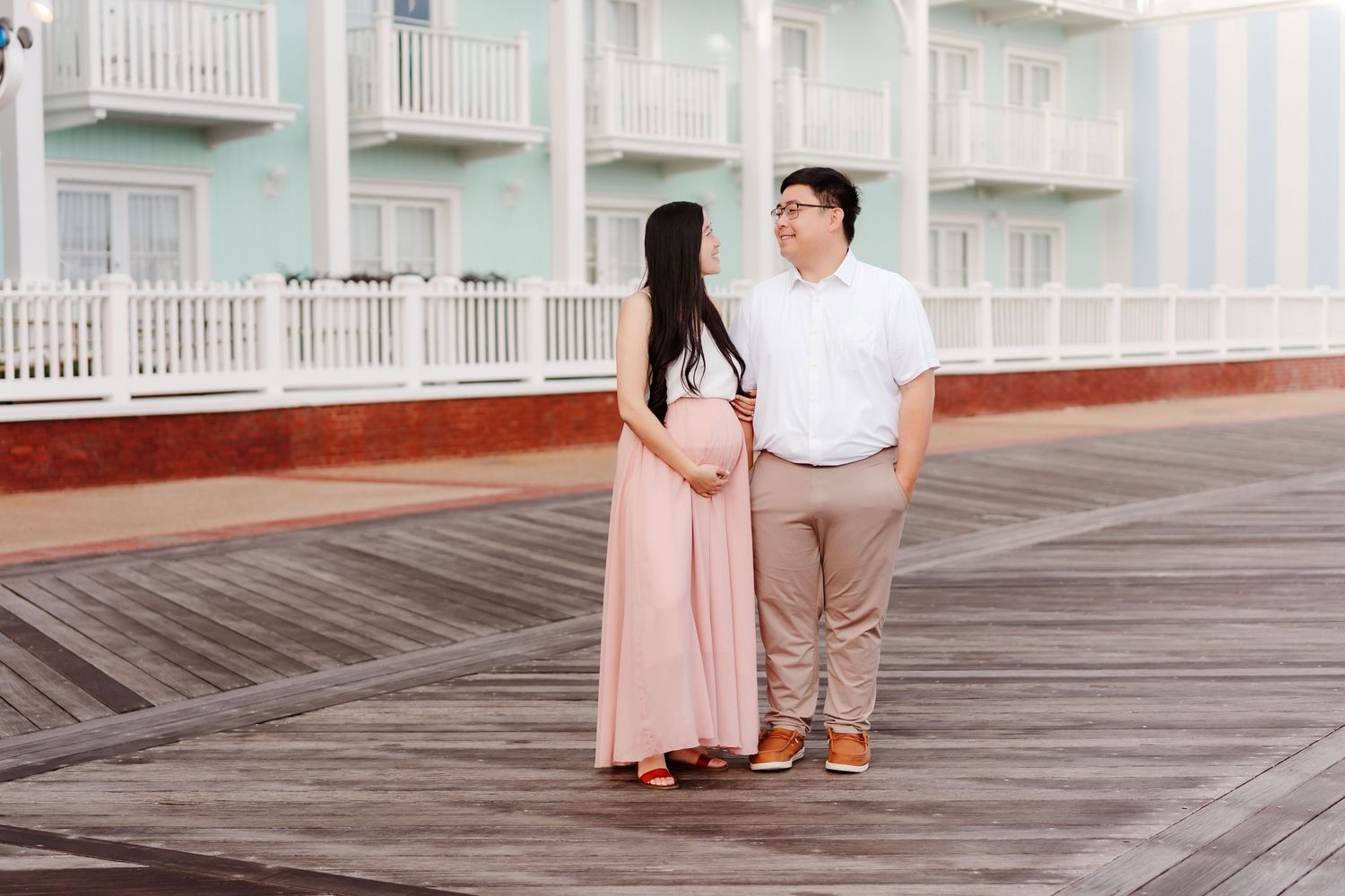 Hands holding ultrasound photo while making heart shape over pregnant belly in pink dress - Windermere, FL