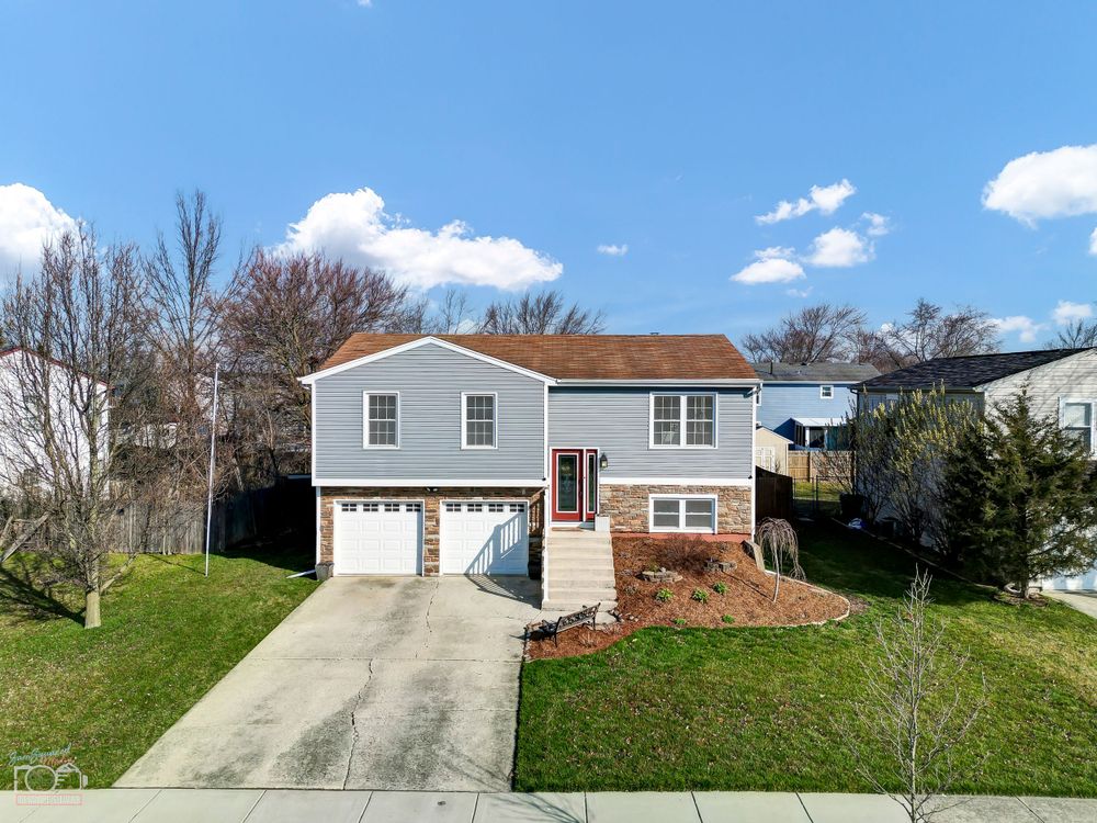 Split-level home with two-car garage and gray siding on a sunny day.