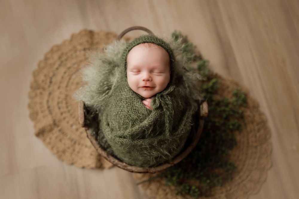Wrapped newborn photography in Magnolia Texas featuring baby posed in a rustic wooden bucket