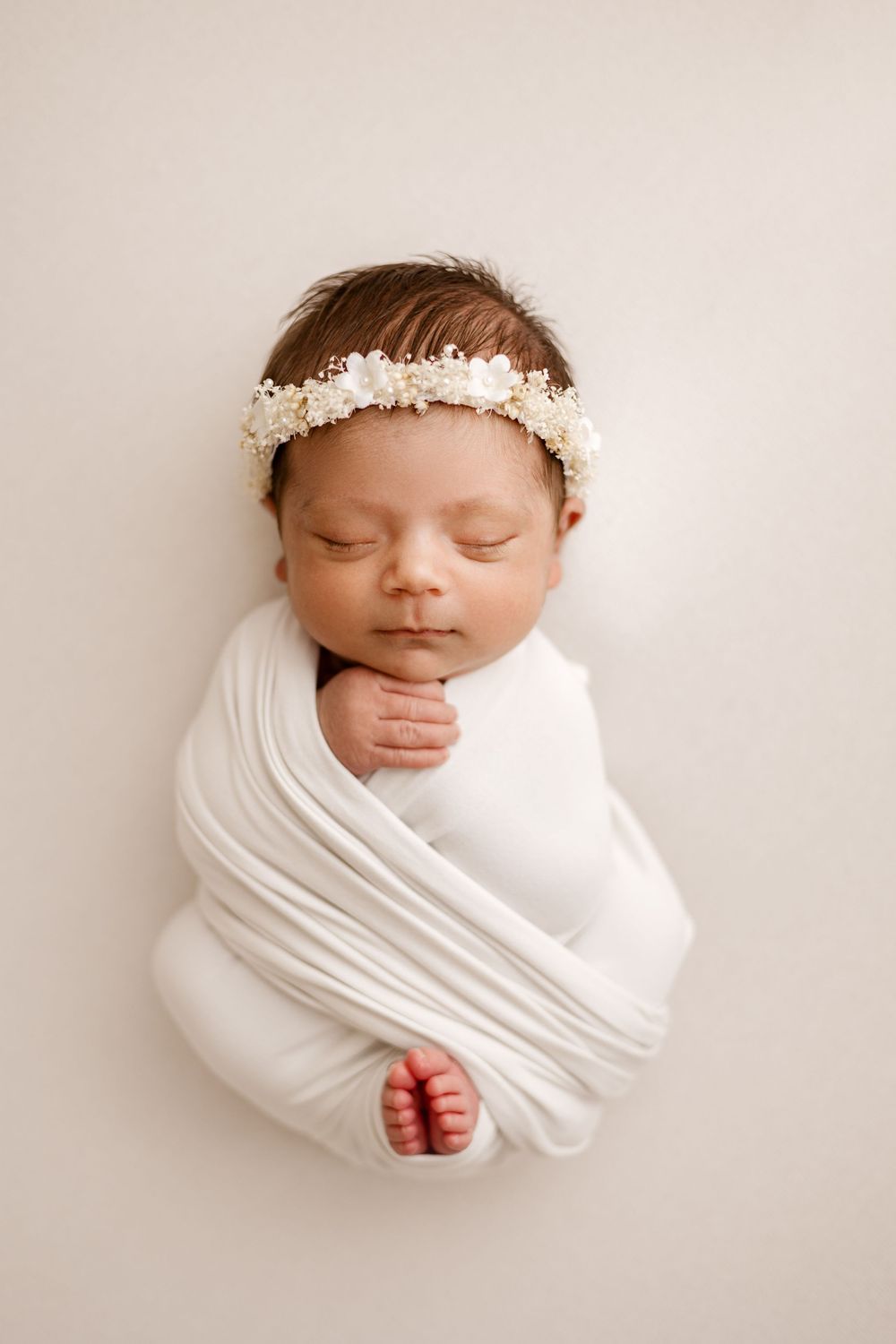 Close-up newborn portrait in Magnolia TX with soft neutral tones and delicate floral headband