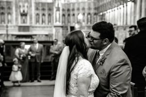 A black and white photograph captures a tender wedding kiss at a grand architectural venue with ornate details. St Dunstan's Basilica PEI