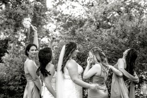 A candid black and white moment of a bridal party posing together outdoors surrounded by greenery. Photo at Montague PEI