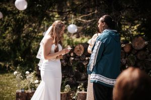 A couple shares an emotional moment during their outdoor wedding ceremony with white paper lanterns decorating the space. Photo on PEI