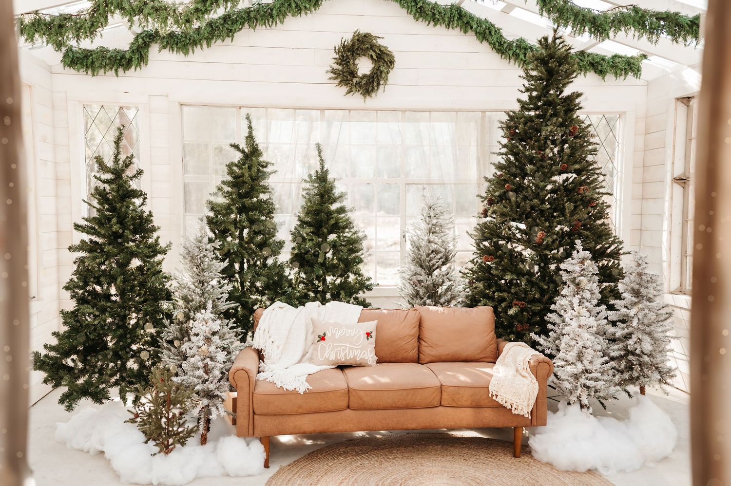 Christmas themed glass house image with green trees, hanging garland, and cozy sofa located in Magnolia, TX