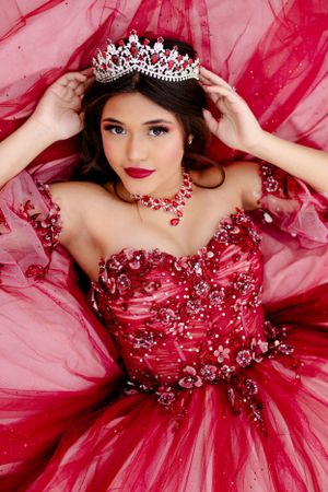 A glamorous red ball gown with sparkles and a crystal tiara creates a stunning formal portrait.