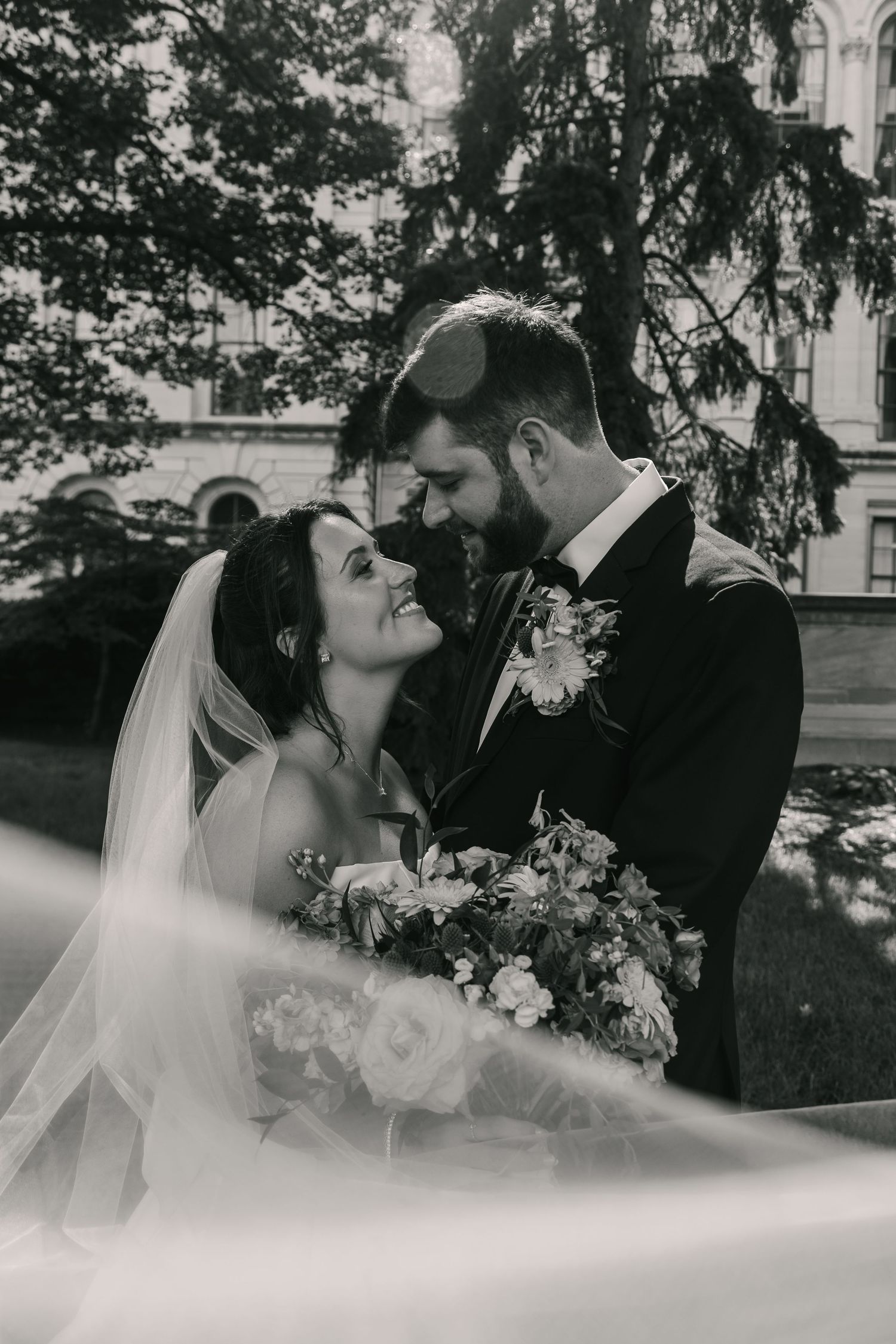 Romantic black and white portrait of newlyweds sharing their first kiss.