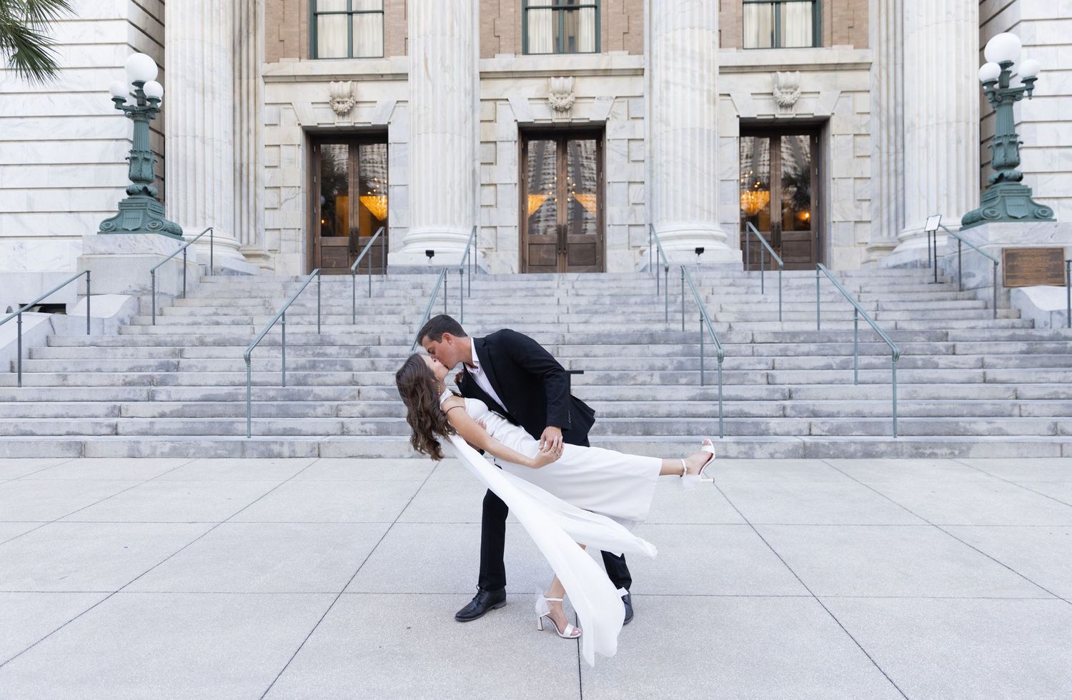 Orlando luxury wedding photographer a couple sharing a romantic kiss in front of a courthouse.