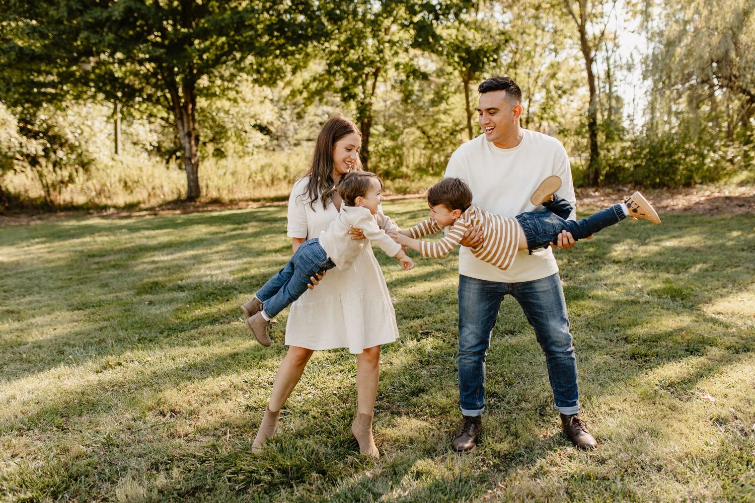 Family playing and having fun together on a grassy hill during golden hour.
