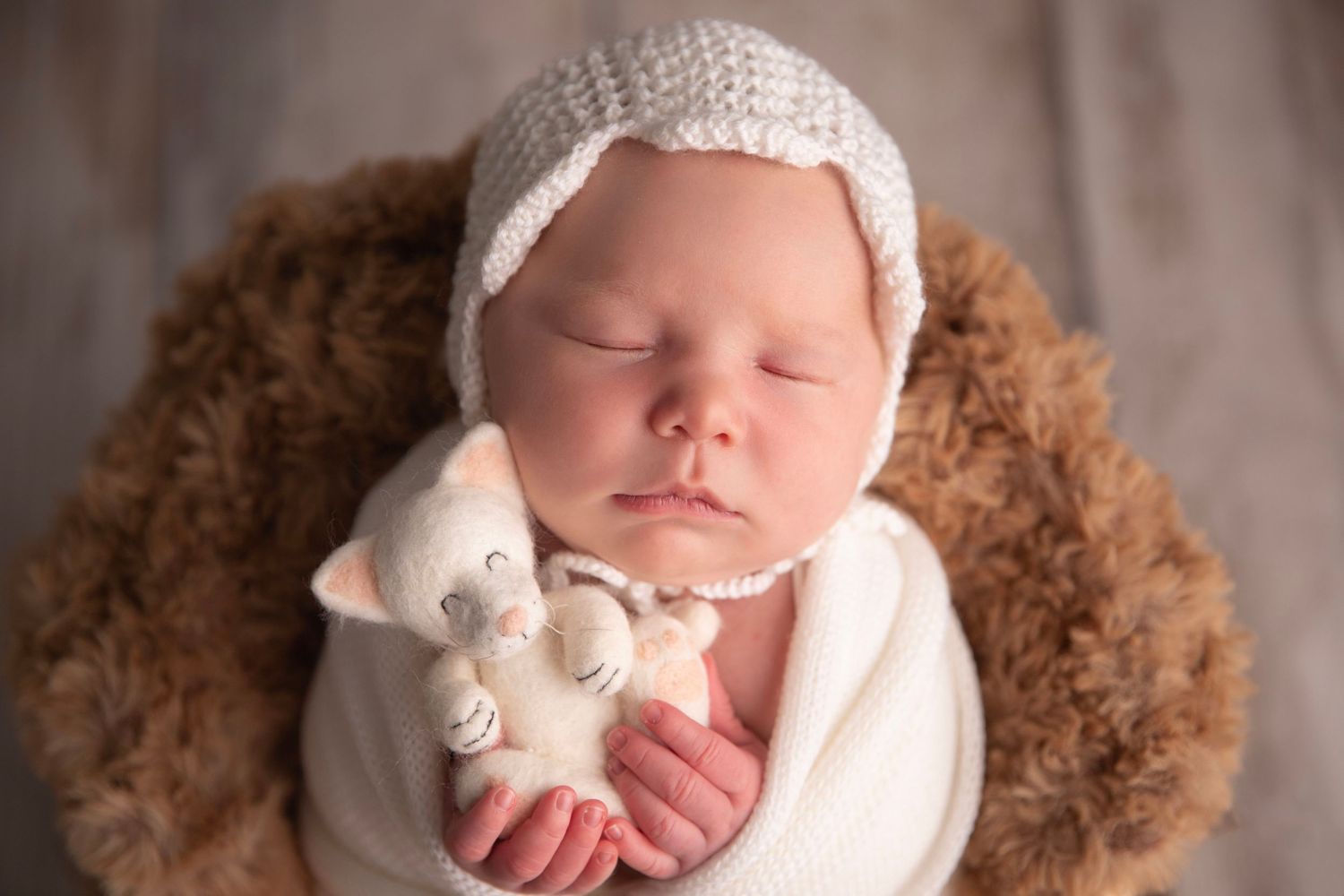 Sleeping newborn baby wrapped in soft textures during Orange City newborn photography session.