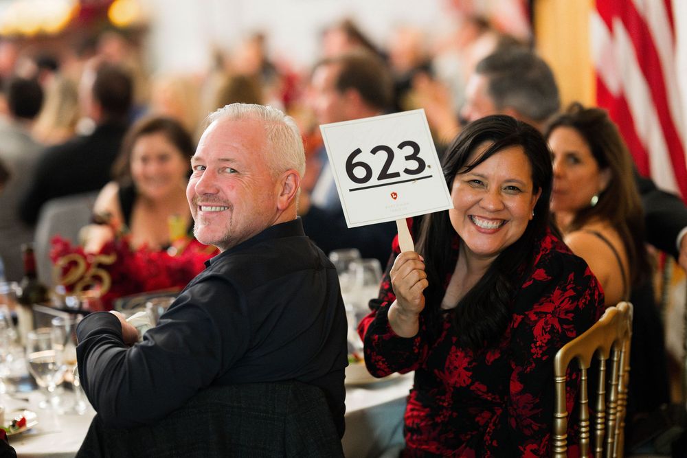 Orange Lutheran High School annual gala attendees hold up a bid sign