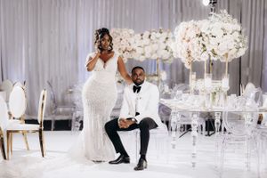 Luxury wedding reception setup featuring a bride and groom in an elegant white and silver decor setting.