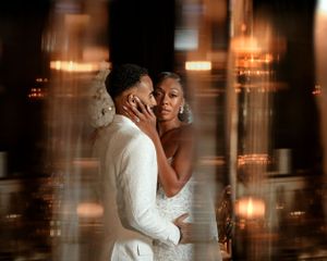 A romantic candlelit wedding moment captured through reflective glass creating a dreamy, atmospheric effect.