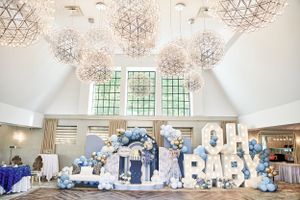 Chic baby shower event decor with ‘Oh Baby’ balloon display, grand chandeliers, and modern event styling.
