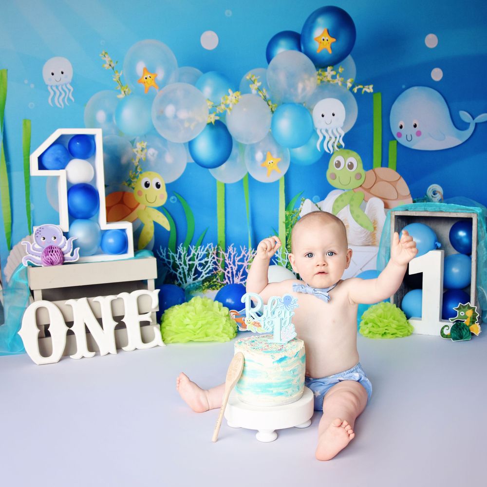 First birthday cake smash under the sea theme. Image of young boy next to his cake ready to smash.