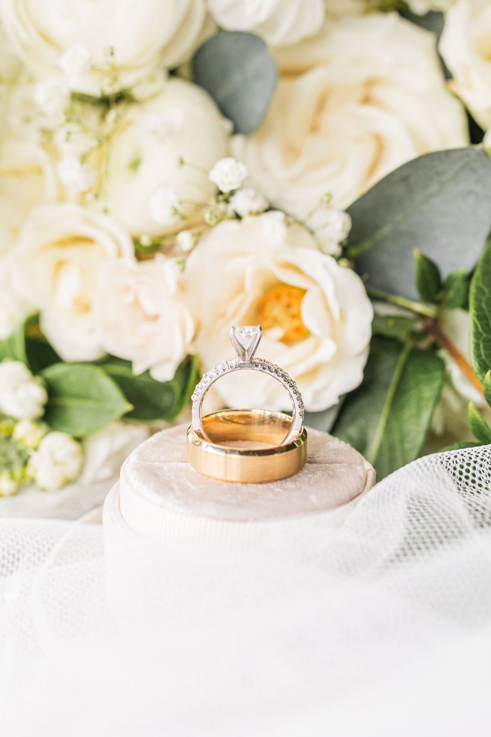 Gold wedding band and diamond ring in front of flowers
