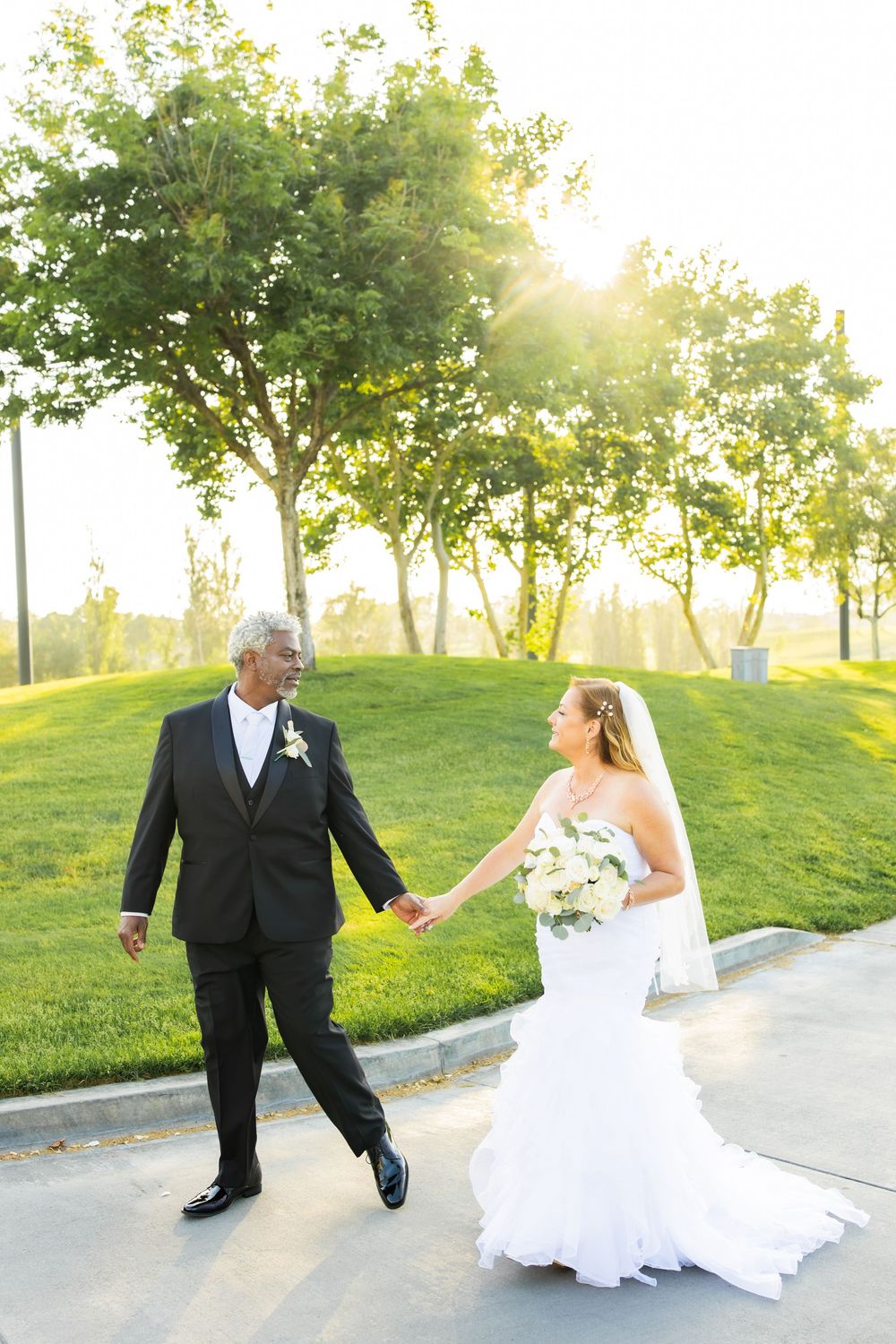 Groom leading bride down path on a golf course