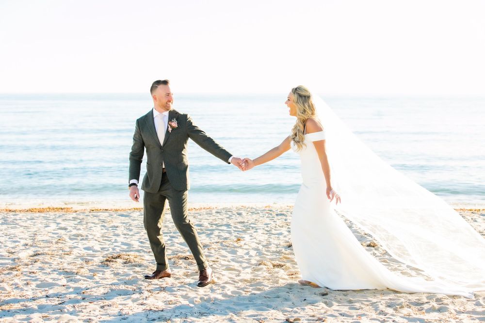 Groom holding brides hand on a beach in Cape Cod
